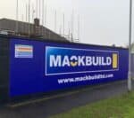 Large hoarding banner for Mackbuild with company logo and website.