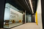 Glass wall with 'Meeting room' sign in a contemporary office space.