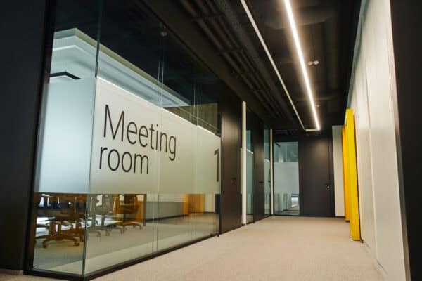 Glass wall with 'Meeting room' sign in a contemporary office space.